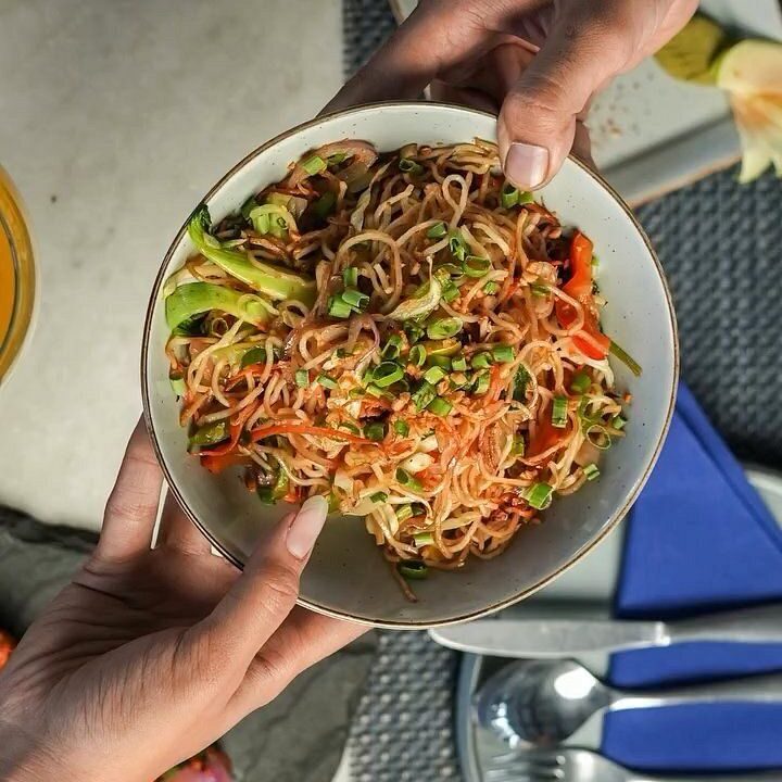 Hands holding noodle bowls at nouba jaipur